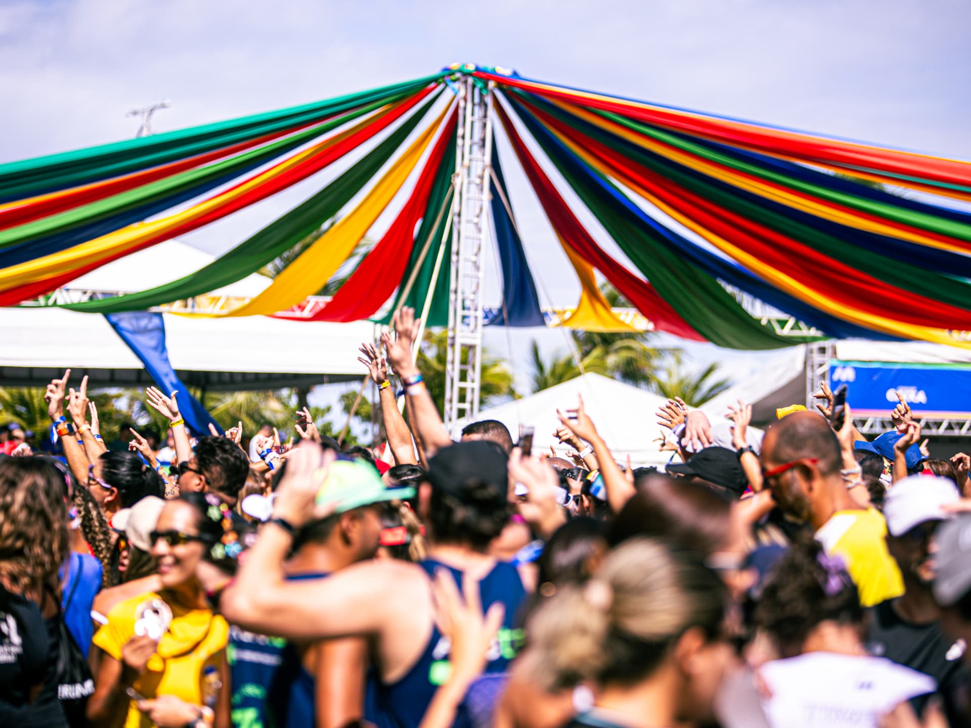 Público dançando sob a tenda colorida da arena